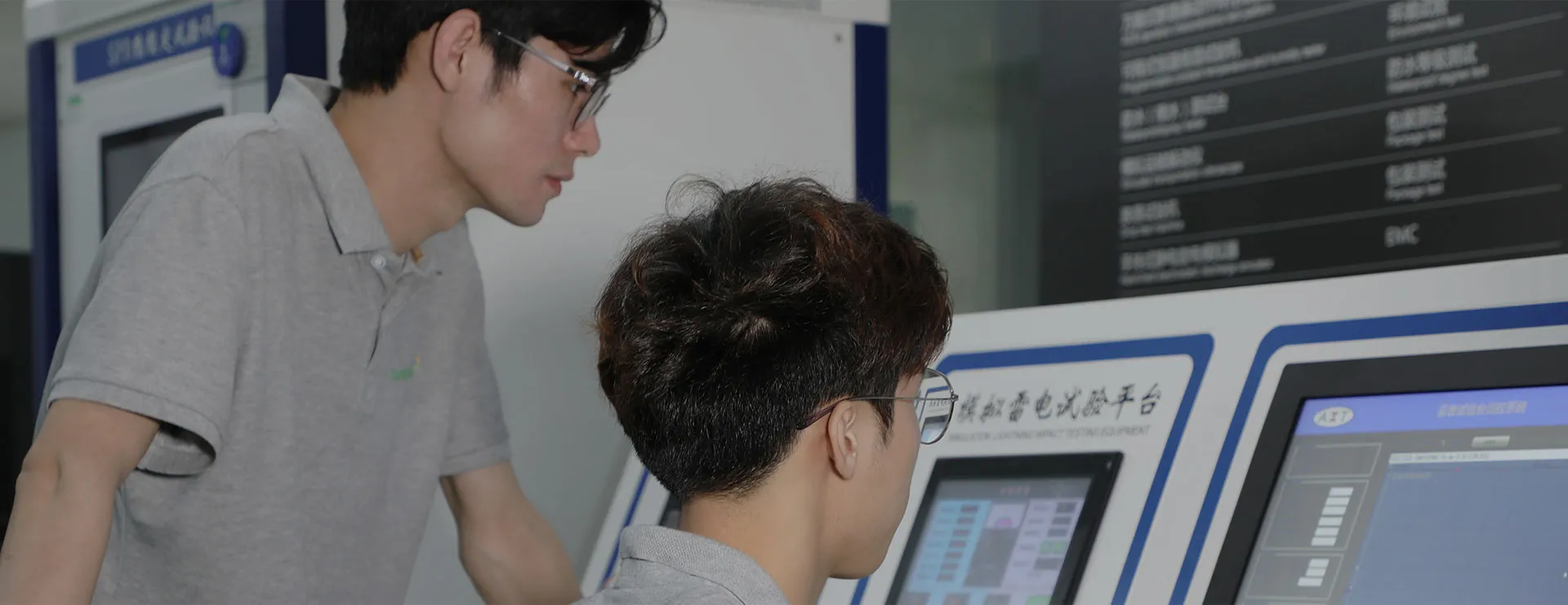 Background image showing two people working on a machine with a blue display panel