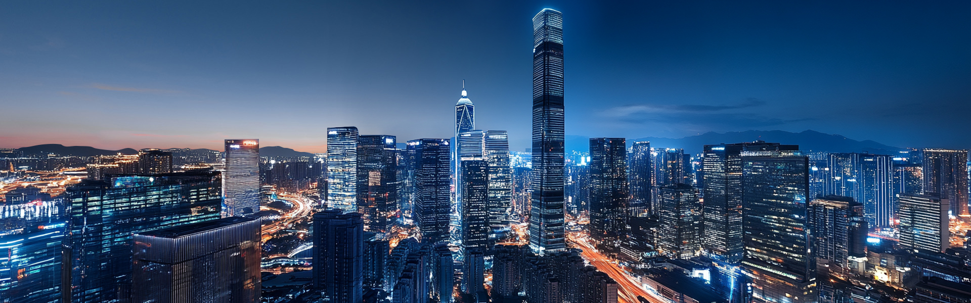 Panoramic view of a modern city skyline with skyscrapers, including a prominent red-tinted building, against a backdrop of green hills and wind turbines in the distance